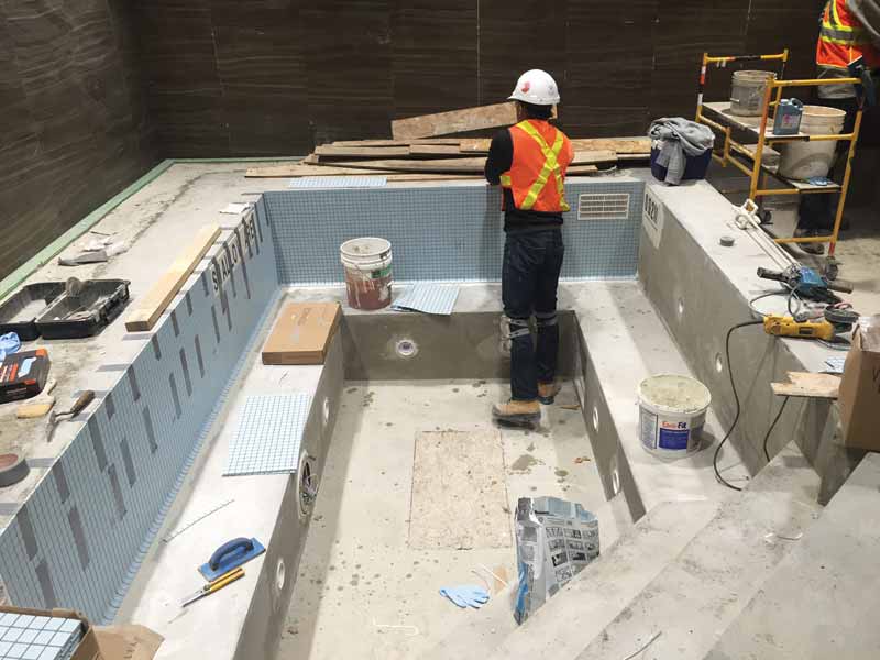 Photo courtesy Acapulco Pools Pool professional tiling a pool surface.