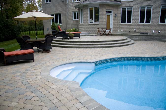 Photo courtesy Roger Willis Contracting Ltd. Poolside interlock concrete paver patio and raised terrace.