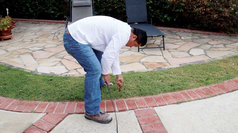 The user inserts the ground rod into the soil near the pool. If the soil is extremely dry, simply using a hose to wet the area before inserting the rod can ensure better results. The user inserts the ground rod into the soil near the pool. If the soil is extremely dry, simply using a hose to wet the area before inserting the rod can ensure better results.