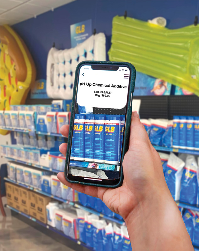 A hand holding up a phone screen in a pool store with the screen displaying text about the product's sale price.