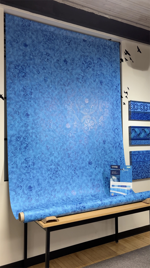 Large blue vinyl sheet featuring the Baia pattern from Poolside by CGT, displayed with product signage and swatch panels.