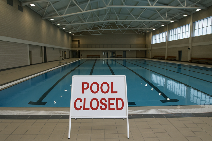 A pool inside a school with a "pool closed" sign in front of it