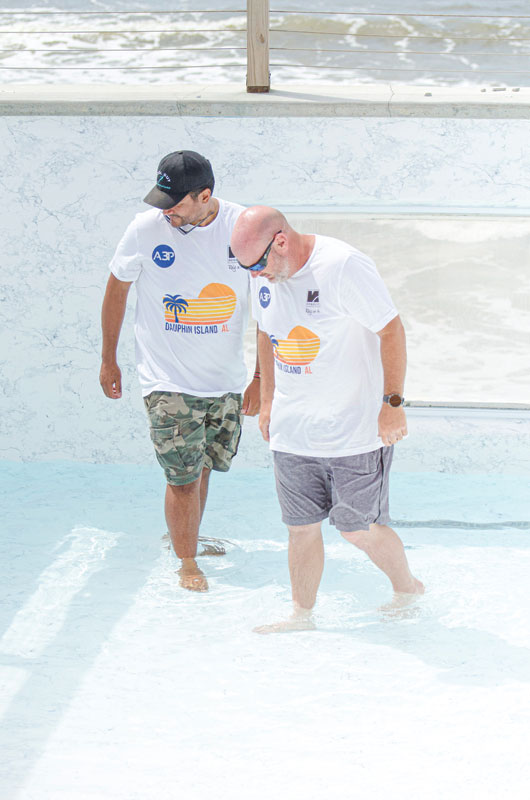 Two workers stand in a completed pool finished with a reinforced polyvinyl chloride (PVC) membrane.