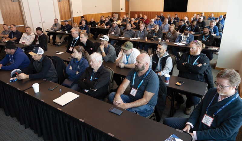 People sit at desks for an exposition.