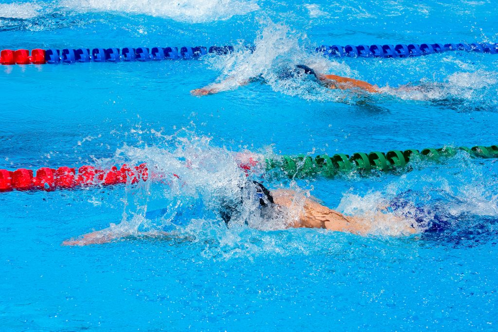 A photo of freestyle swimmers in an outdoor swimming pool.