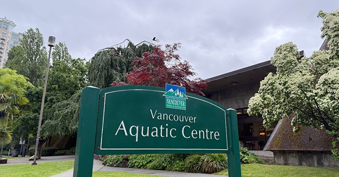 Green Vancouver Aquatic Centre sign surrounded by trees and landscaping.