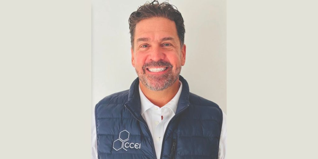 Smiling man in a white collared shirt and navy quilted vest with a CCEI logo.